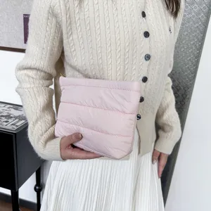 Detailed shot showing a stylish pink quilted clutch bag held in hand by a model.