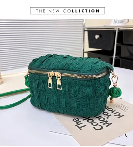 Detail view of dark green textured quilted vanity crossbody bag with gold hardware and knotted charm details.