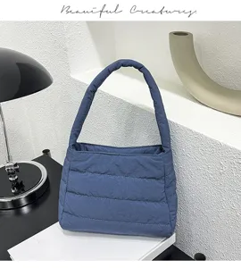 Detail view of stylish blue quilted puffer shoulder bag in minimal modern setting display.
