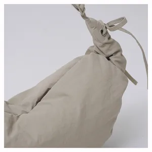 Detail shot of casual nylon dumpling bag featuring gathered pleats, drawstring and metal eyelet.