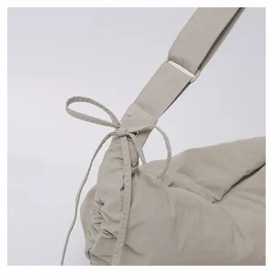 Detailed view of women casual pleated nylon shoulder bag with bow tie and wide strap.