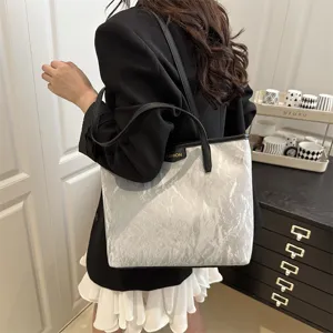 Detail view of stylish silver textured shoulder tote bag with black trim for women daily use.
