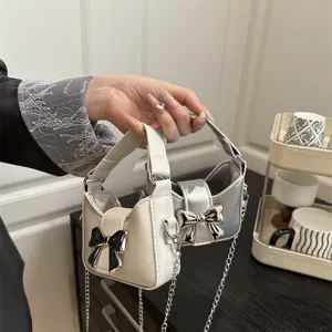 Detailed view of children mini handbag with cute bow and metal chain strap in daily life scene.