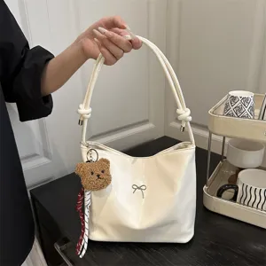 White glossy shoulder bucket bag with cute bear keychain and stylish bow detail for women.