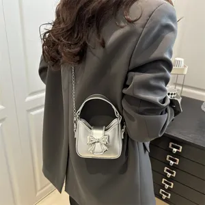 Detailed view of the silver mini handbag with metallic bow and chain strap, stylish design.