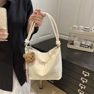 Detailed view of the minimalist shiny white shoulder bucket bag featuring cute bear charm.