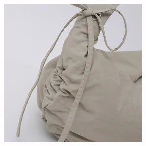Close up of casual nylon dumpling shoulder bag featuring ruched drawstring detail and strap.