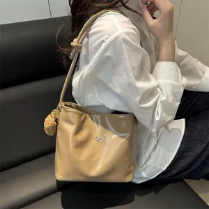 Minimalist shiny PU leather shoulder bucket bag with bow detail and cute pom-pom charm.
