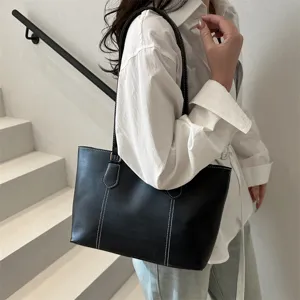 Détail de sac cabas en cuir souple noir, sac porté épaule décontracté minimaliste.