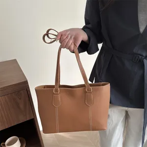 Gros plan de l'élégant sac cabas marron en cuir souple avec de belles surpiqûres fines.