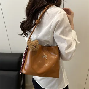 Brown glossy bucket shoulder bag with cute bear pendant, bow decor and stylish shoulder strap