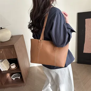 Vue détaillée du sac cabas en cuir souple marron porté à l'épaule, style quotidien.