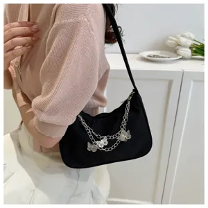 Detalle de primer plano de elegante bolso negro al hombro con cadenas de mariposa.