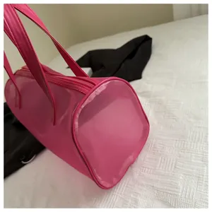 Pink translucent cylindrical mesh handbag detail view showing portable shoulder strap design.
