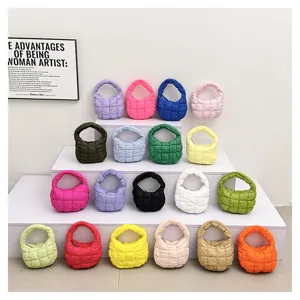 Detailed shot of colorful quilted mini cloud bags displayed on white tiers, trendy style.