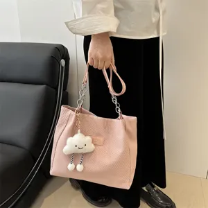 Close-up of pink corduroy tote bag featuring cute cloud plush charm and metallic chain strap detail.