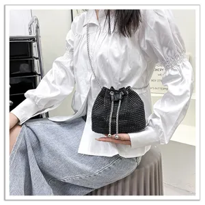 Gros plan d'un sac seau noir scintillant en strass avec bandoulière chaîne et boules.