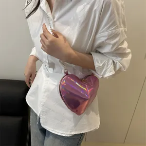 Pink iridescent heart shaped crossbody bag detail close up, glossy patent leather texture and chain.