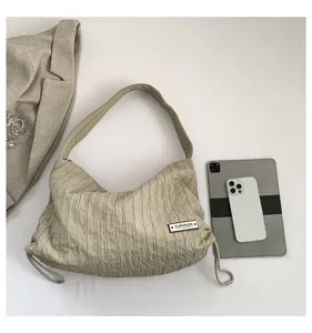 Detailed view of the casual beige pleated shoulder bag with chic drawstring and texture.