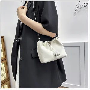 Detailed shot of the white drawstring bucket bag showing its elegant chain strap and clasp.