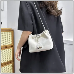 Close-up of white shoulder bucket bag with chain strap, soft texture and cute bow detail.