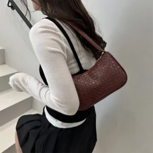 Detailed shot of burgundy woven shoulder underarm bag, classic intrecciato pattern lifestyle.