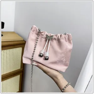 Pink velvet bucket bag featuring metal chain strap and cute butterfly drawstring detail.