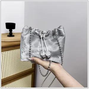 Detailed view of a stylish silver metallic bucket bag with chain strap and cute butterfly accent.