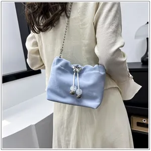 Detail shot of a stylish light blue bucket bag with chain strap and butterfly charm.