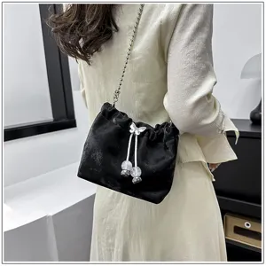 Detailed view of black velvet bucket bag, crystal butterfly decor and chic metal chain strap.