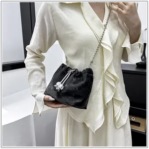 Detailed view of fashionable black bucket bag with chain strap and drawstring design.