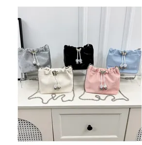Detailed view of fashionable velvet bucket handbags with metal chain straps and cute charms.
