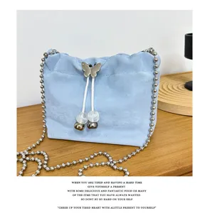 Light blue velvet bucket bag detail, featuring cute butterfly drawstring and metal chain strap.