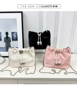 Detailed view of trendy velvet bucket bag with chain strap, bow pearl drawstring, chic showcase.