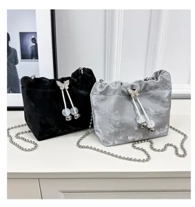 Velvet bucket bag detail featuring butterfly drawstring, clear beads, and chain strap.