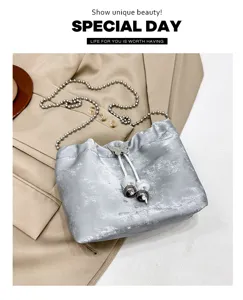 Stylish silver metallic bucket bag with chain strap and chic butterfly drawstring detail.