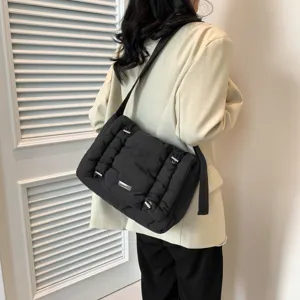 Zwarte gewatteerde schoudertas voor dames, stijlvolle crossbody tas met metalen details.