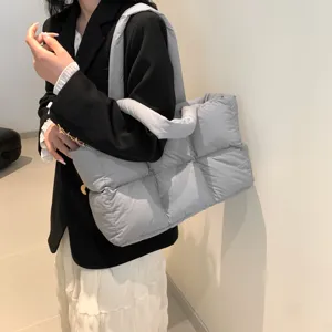 Close-up detail of the stylish grey quilted puffer tote bag worn with a black blazer.