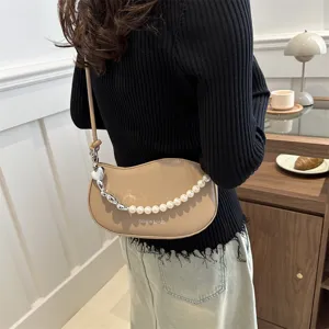 Detail view of the stylish beige curved shoulder bag with pearl and silver chain strap detail.