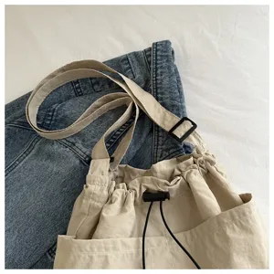 Detailansicht einer lässigen Khaki Kordelzug Umhängetasche mit mehreren Taschen und Riemen.