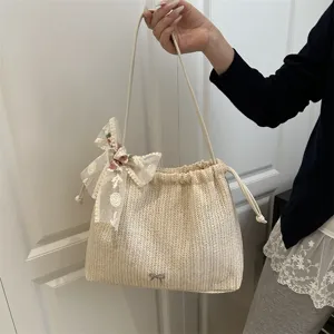 Detail shot of women's woven straw shoulder bag with lace bow, showing texture and craft.