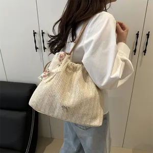 Detailed view of women woven straw shoulder bag, large capacity tote with bow and floral scarf.