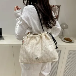 Detailed view of the stylish woven straw shoulder bag with delicate bow and scarf accent.