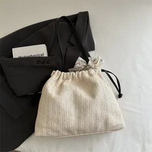 Woven straw bucket shoulder bag for women, casual tote with black straps and stylish scarf.