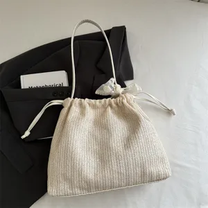 Woven straw bucket shoulder bag detail, drawstring closure with elegant lace bow ribbon.