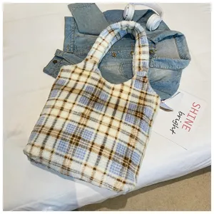 Detailed shot of a fuzzy plaid tote bag, soft fleece shoulder bag styled with denim jacket.