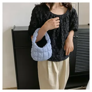 Detailed shot of a stylish light blue quilted puffer underarm bag with unique pleated design.