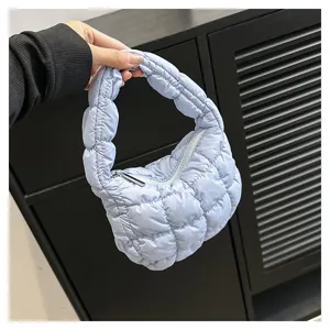 Close-up of light blue quilted puffer cloud bag, mini handbag zipper detail, soft puffy texture.