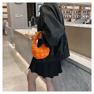 Close-up shot of the trendy orange quilted cloud puffer bag styled in a modern setting.