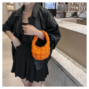 Detail view of a trendy orange quilted cloud underarm bag, fluffy mini fashion handbag design.